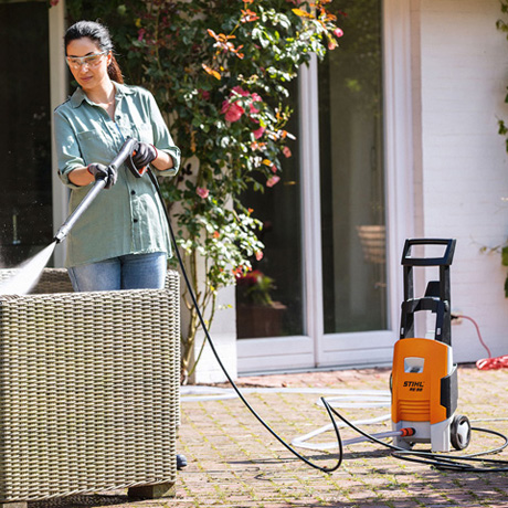 Woman using STIHL high pressure cleaner to clean her ratan chair